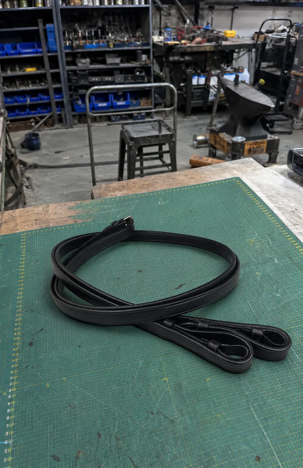 Black leather reins inspected on a workshop table